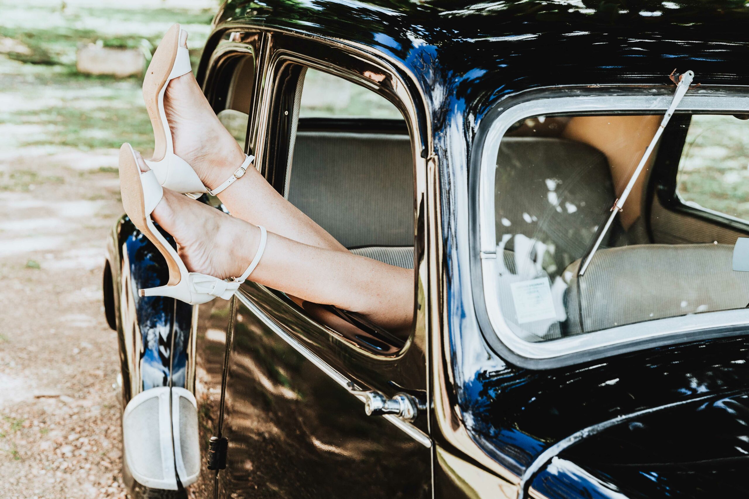 photo de mariage originale. les chaussures de la mariés dépassent de la fenêtre d'une voiture vintage