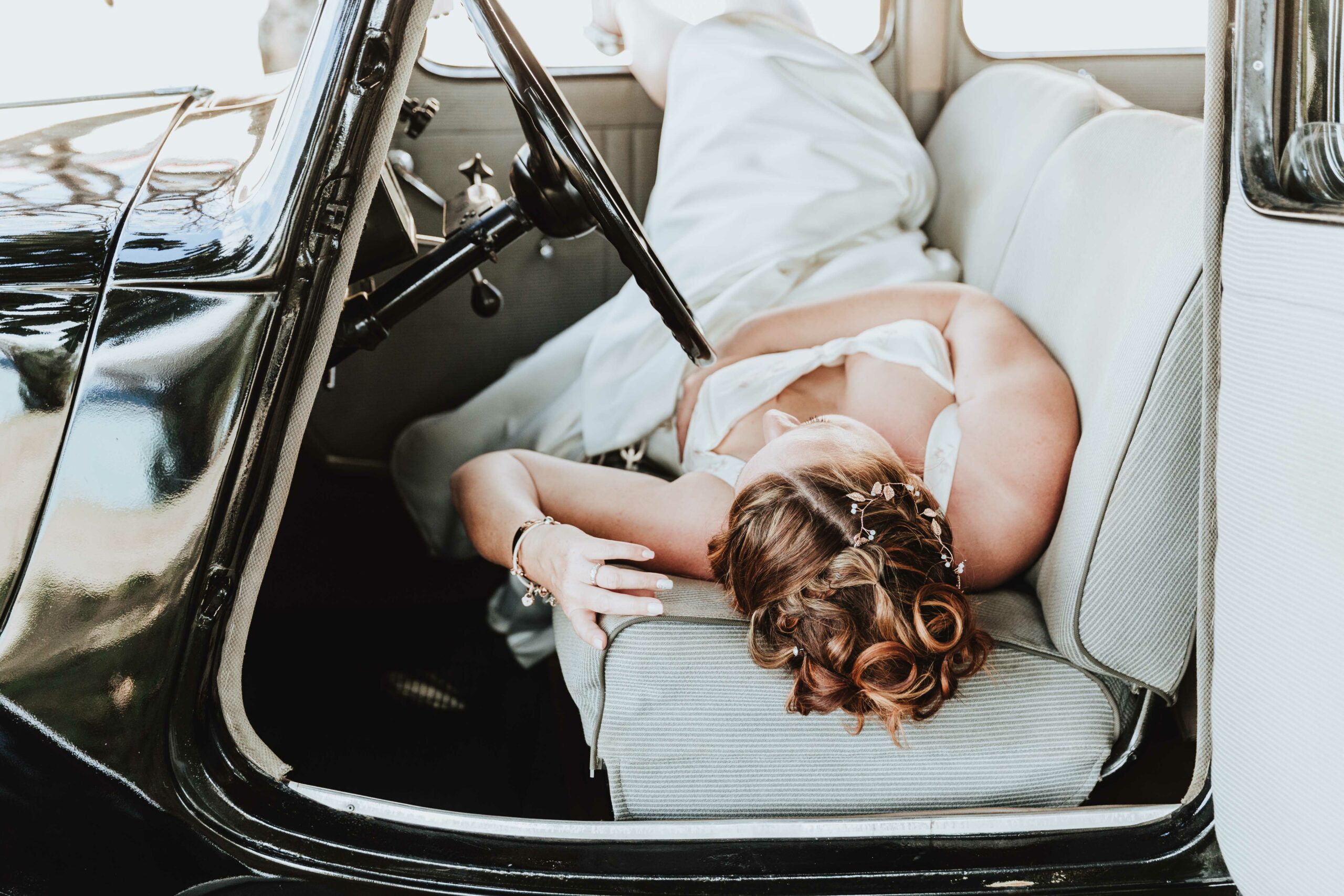 la mariée est allongée dans une voiture rétro