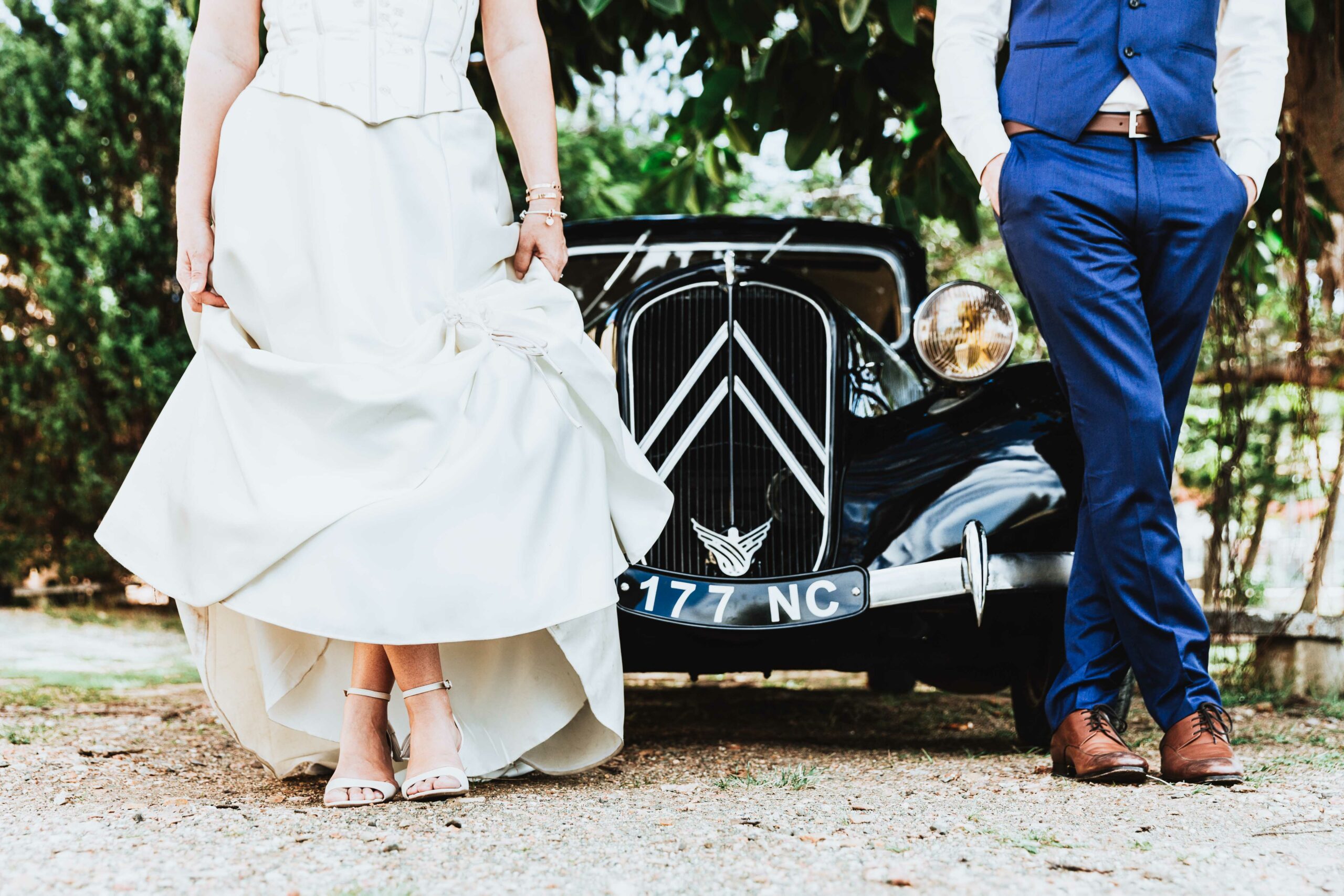 détail des jambes des mariés devant une voiture vintage