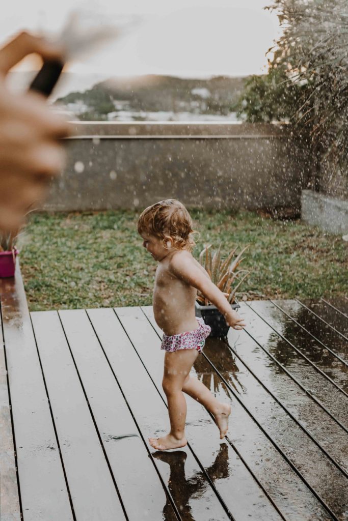 photographe famille lifestyle à domicile, immortaliser des moments de complicité et de douceur dans votre environnement quotidien. Les enfants jouent sous la pluie dans leur jardin à Mulhouse, Haut-Rhin