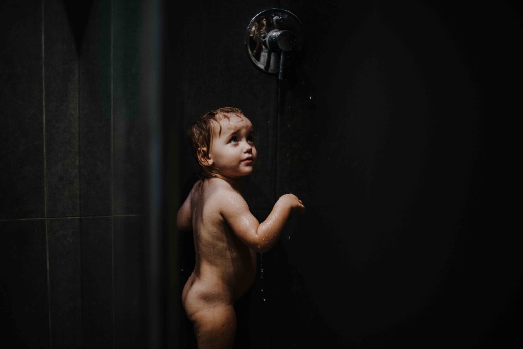 photographe famille lifestyle à domicile en Alsace, Haut-Rhin, Mulhouse, Colmar, Altkirch. La petite fille joue sous la douche.