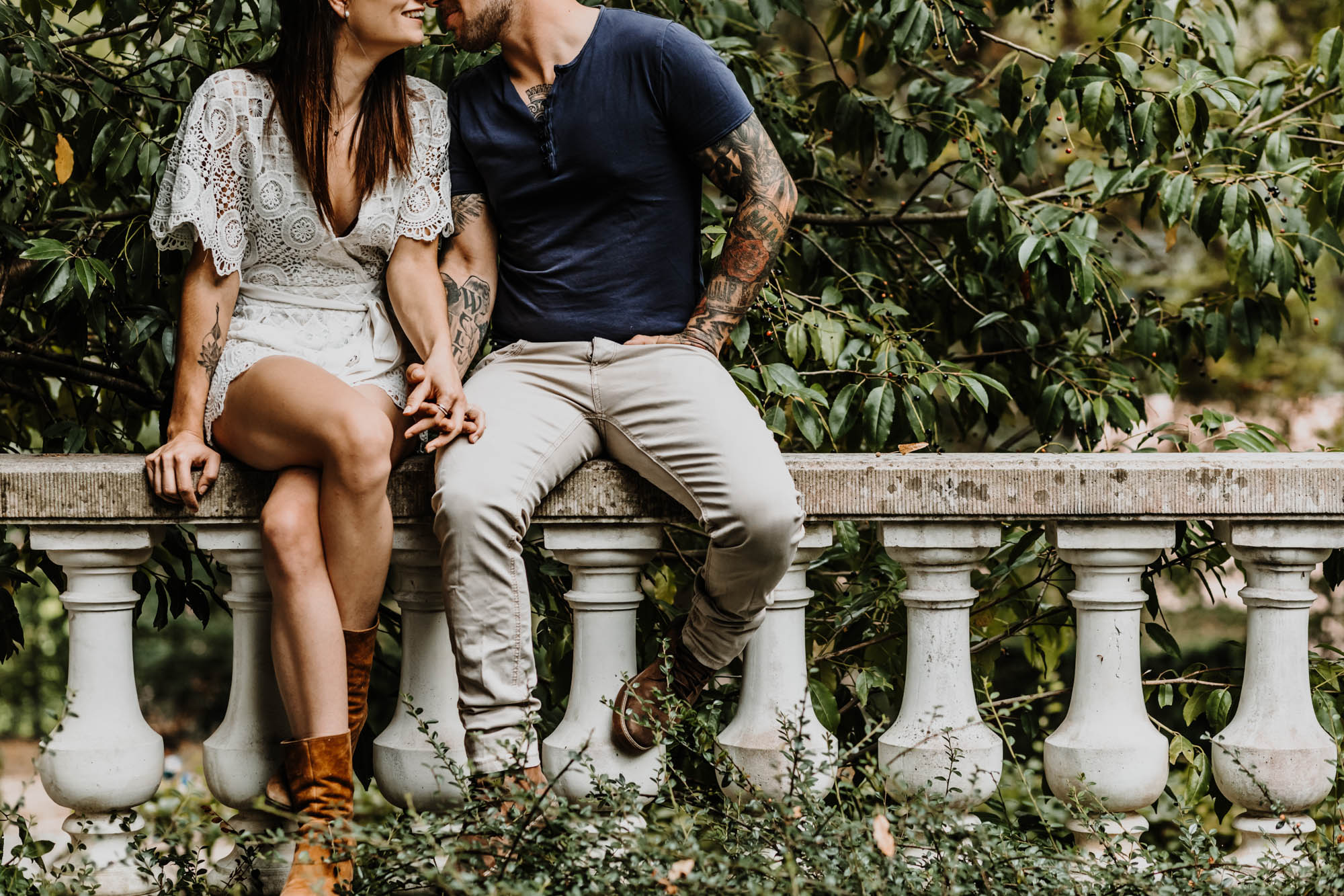 couple assis sur un muret se tient la main, s'embrassent