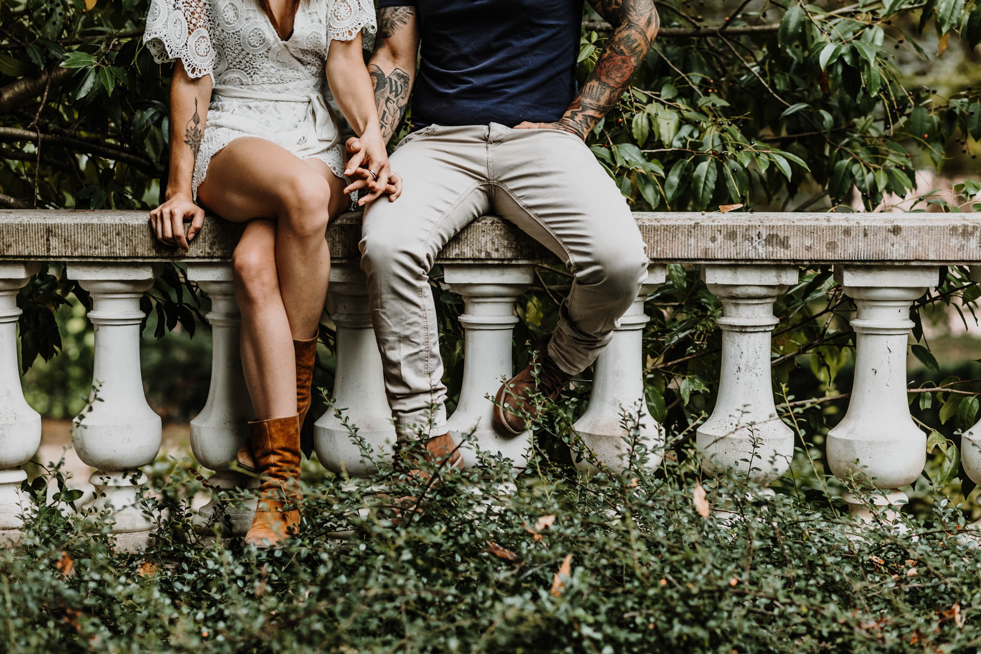 couple assis sur un muret dans un parc, ils se tiennent la main