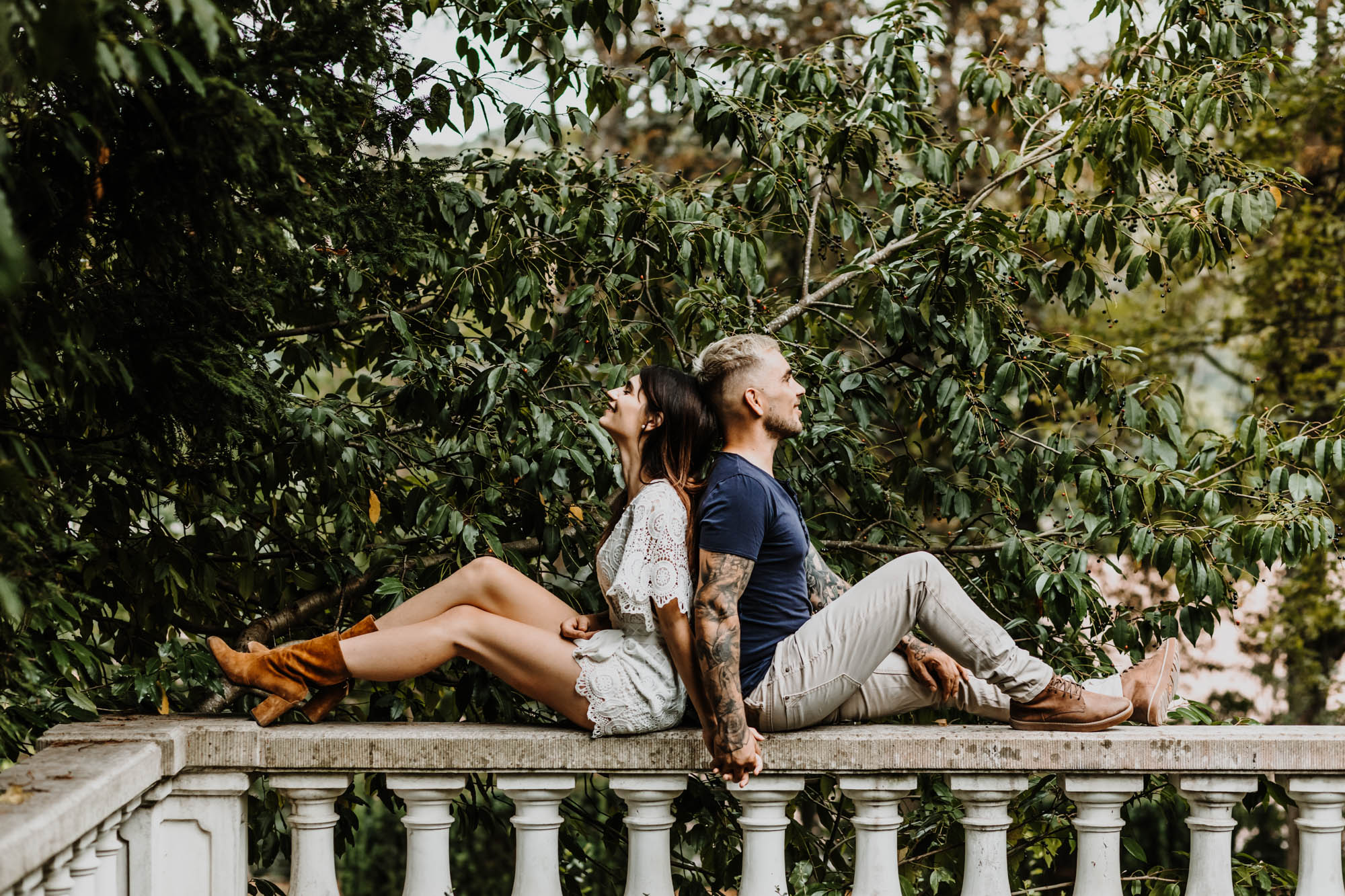 couple assis dos à dos sur un muret dans un parc