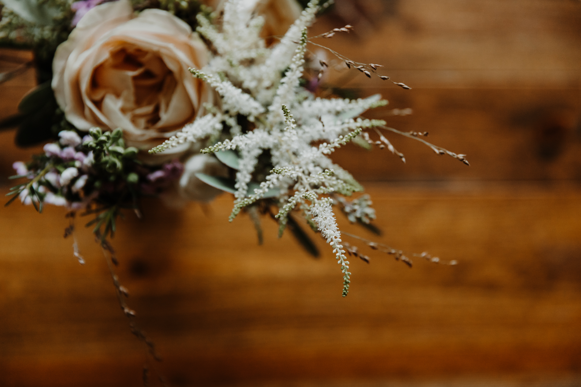 détail du bouquet de la mariée posé sur un meuble en bois