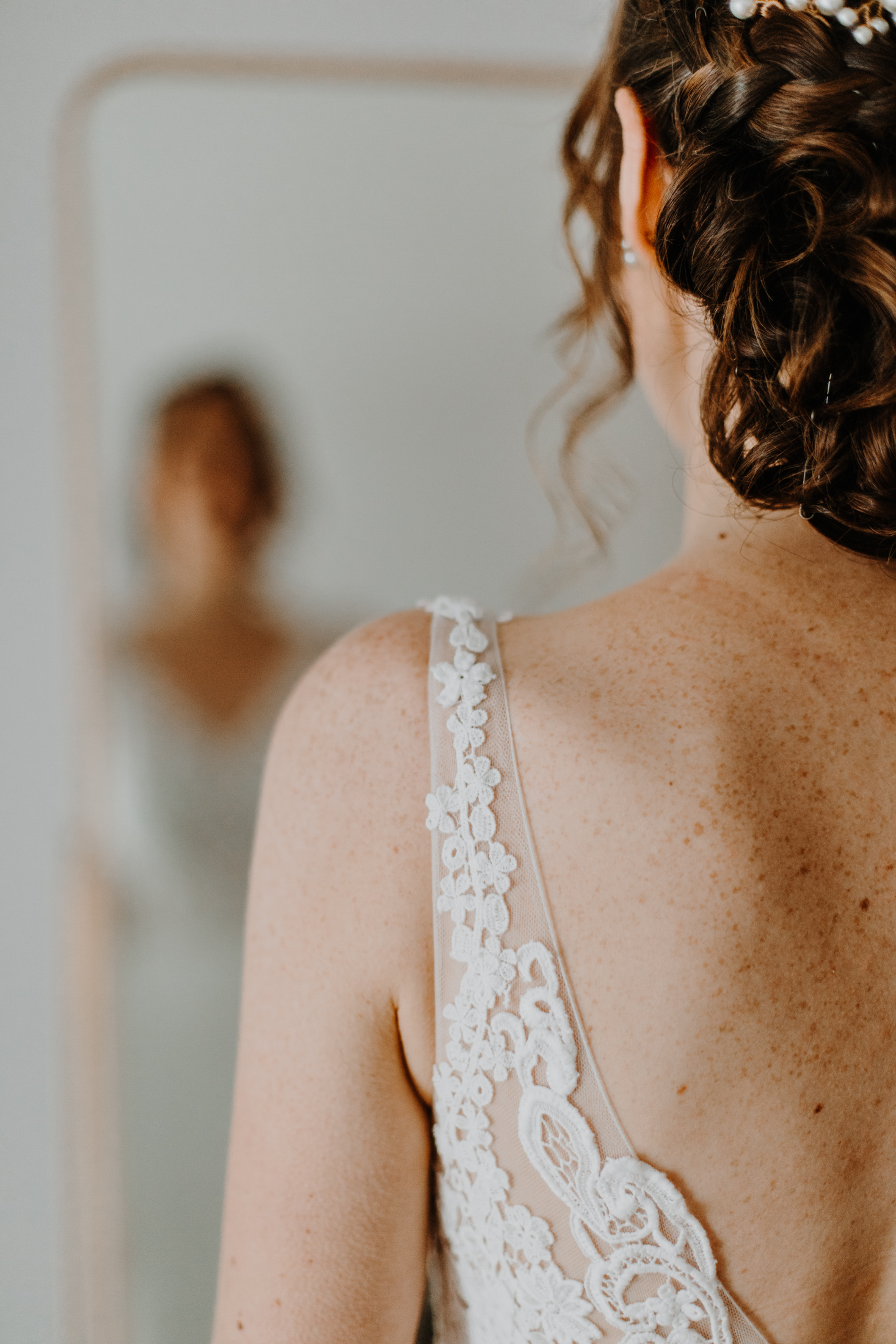 la mariée se regarde dans le miroir, détail de son épaule