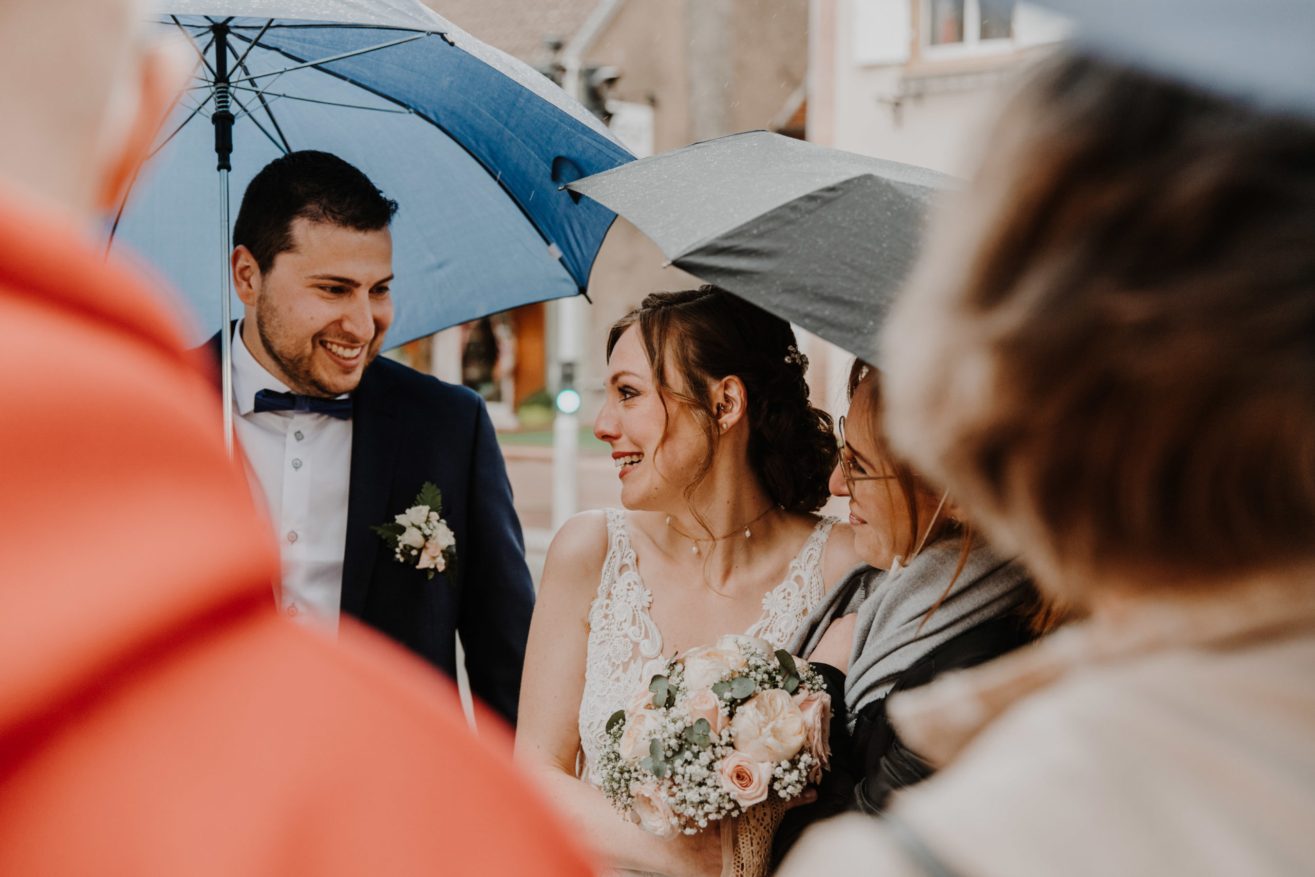 les mariés partis leurs invités à la sortie de la mairie, sous des parapluies