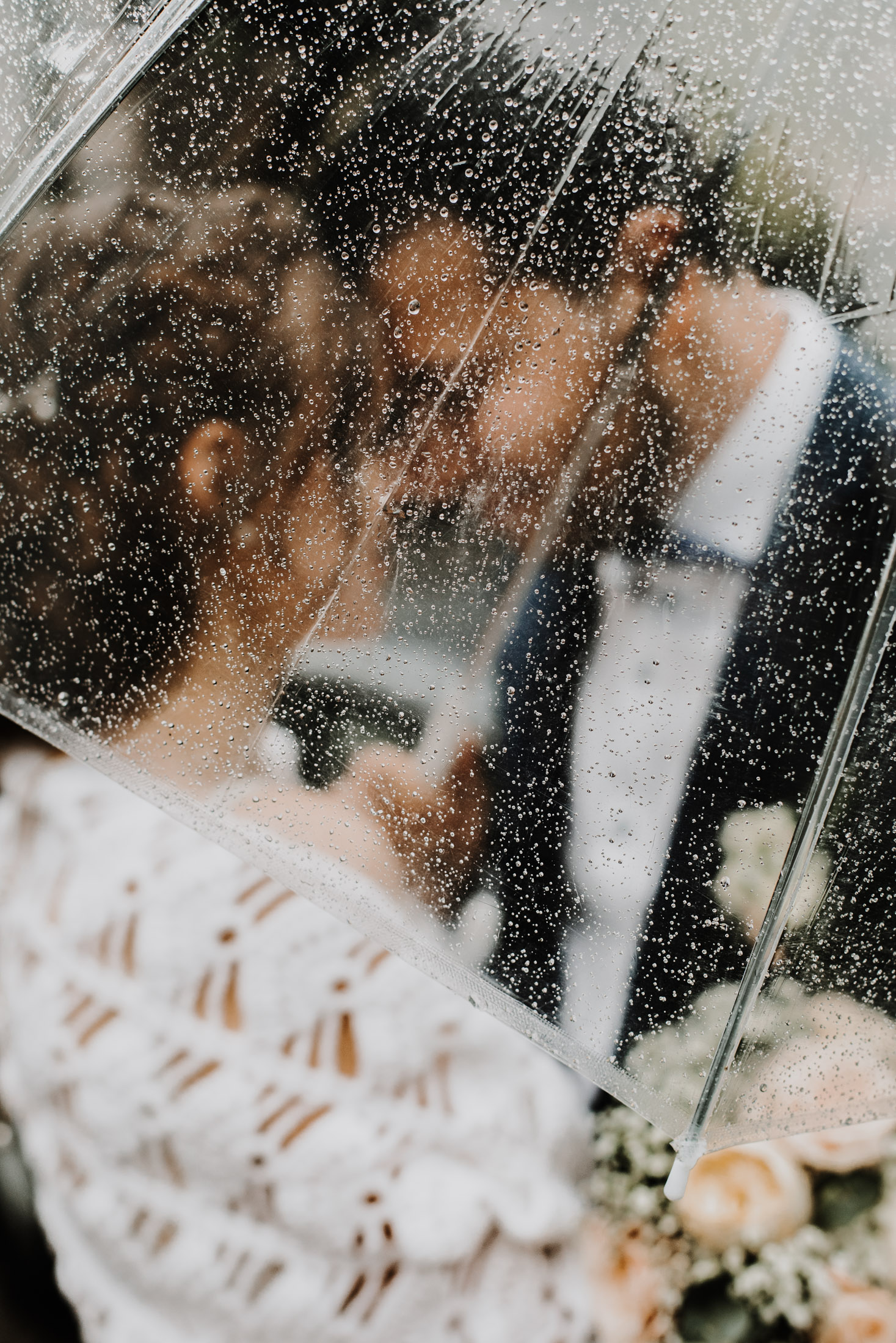 les mariés face à face, enlacés sous un parapluie trnasparent
