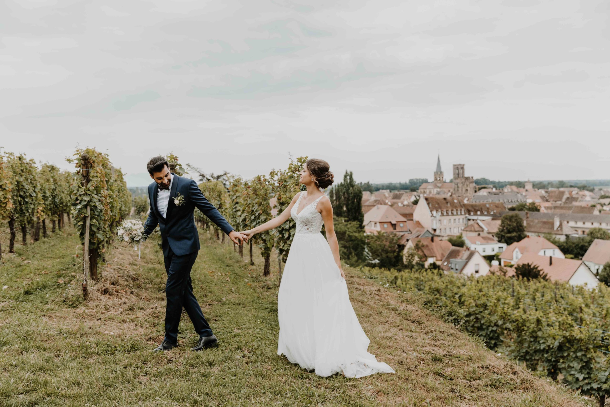 les mariés marchent main dans la main dans le vignoble alsacien 