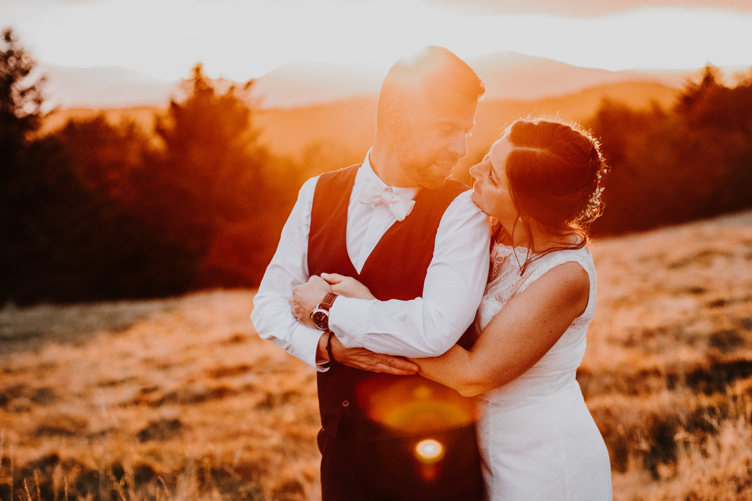 couple de mariés enlacés dans un paysage de montagne au coucher su soleil