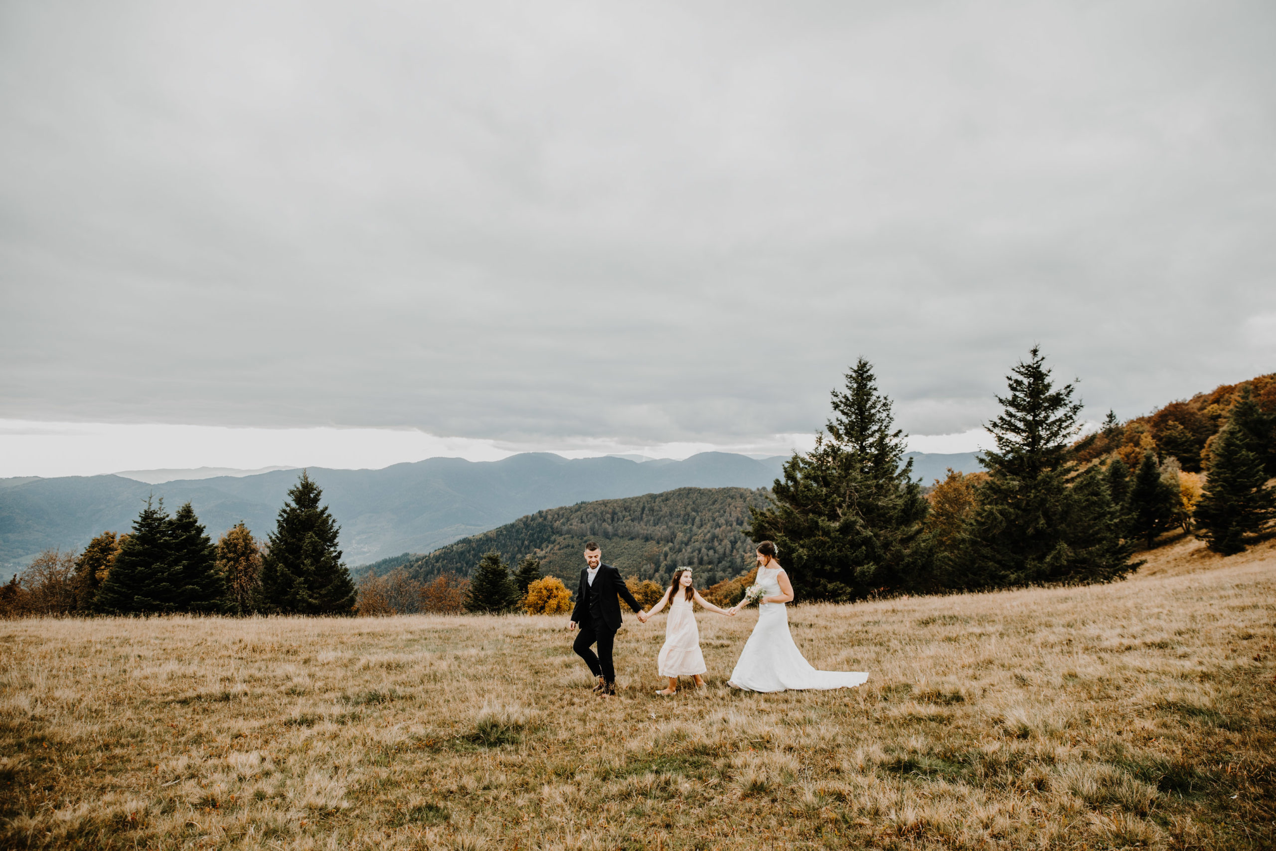 couple de mariés marchent mains dans la main avec leur filles dans la montagne