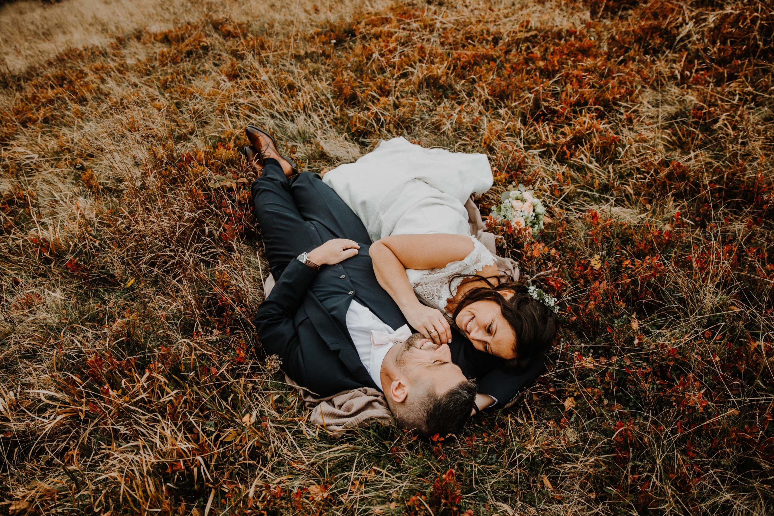 couple de mariés allongés dans l'herbe à l'automne 