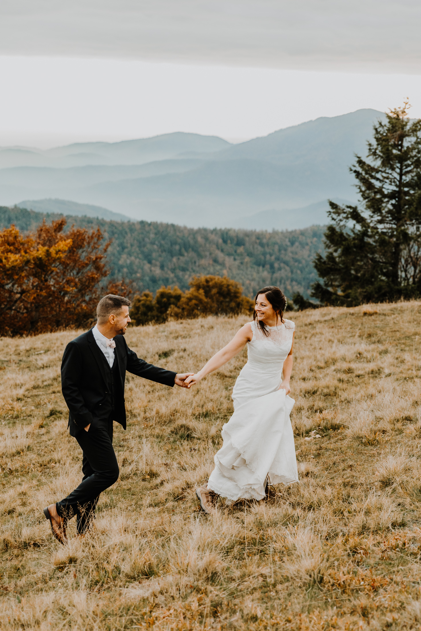 couple de mariés marchent en montagne en riant