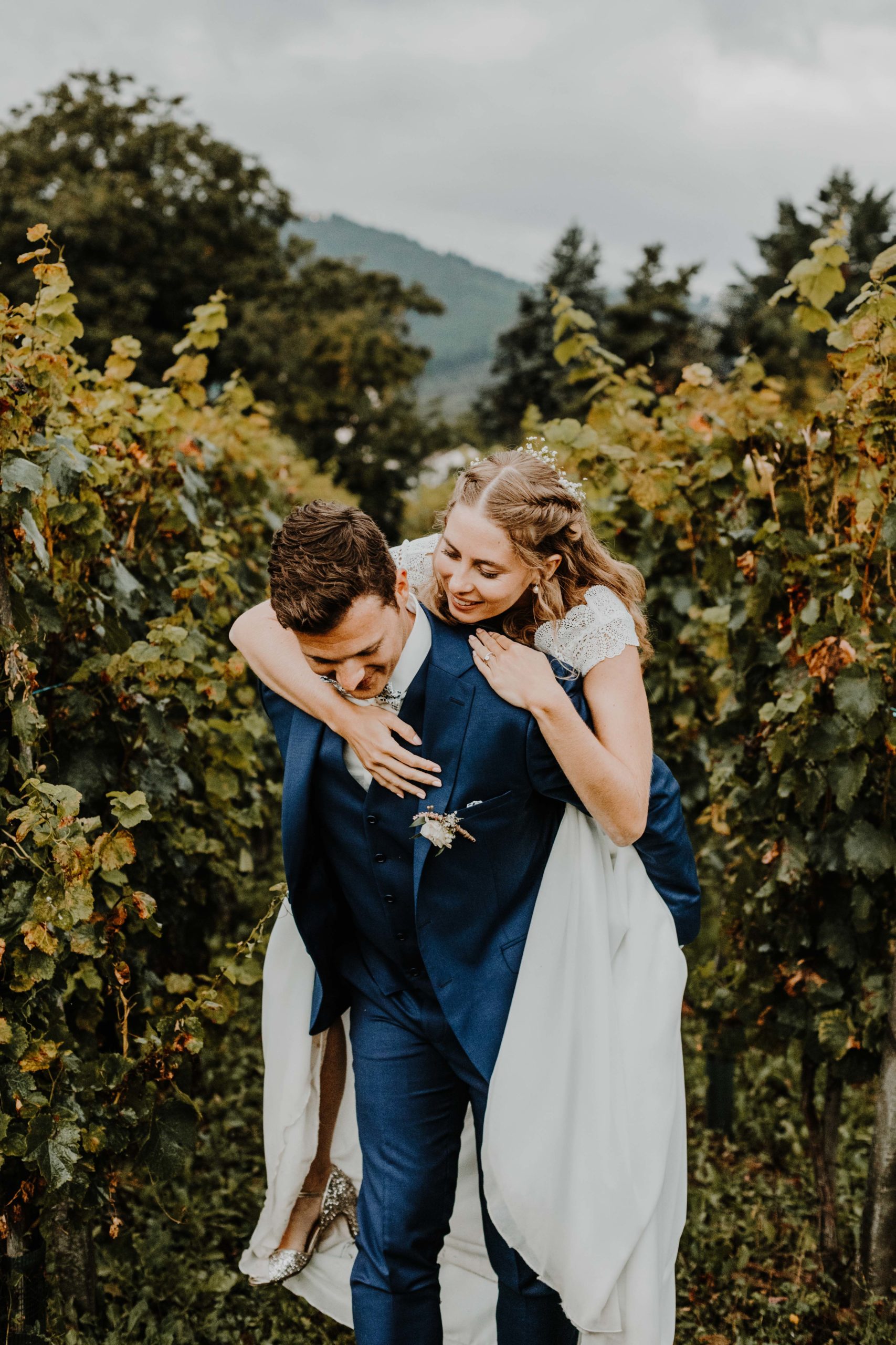 couple de mariés dans le vignoble, la mariée saute sur le dos de son mari
