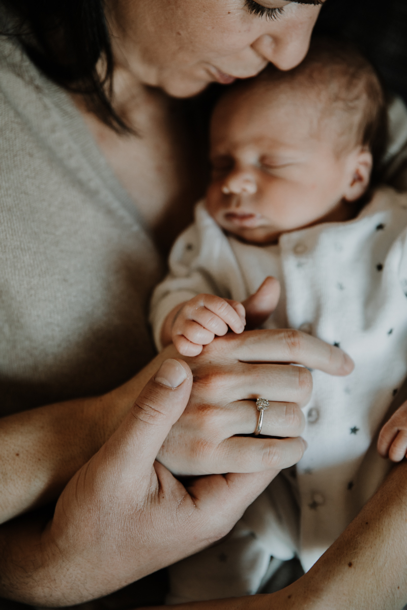 détail des mains du bébé dans les bras de maman