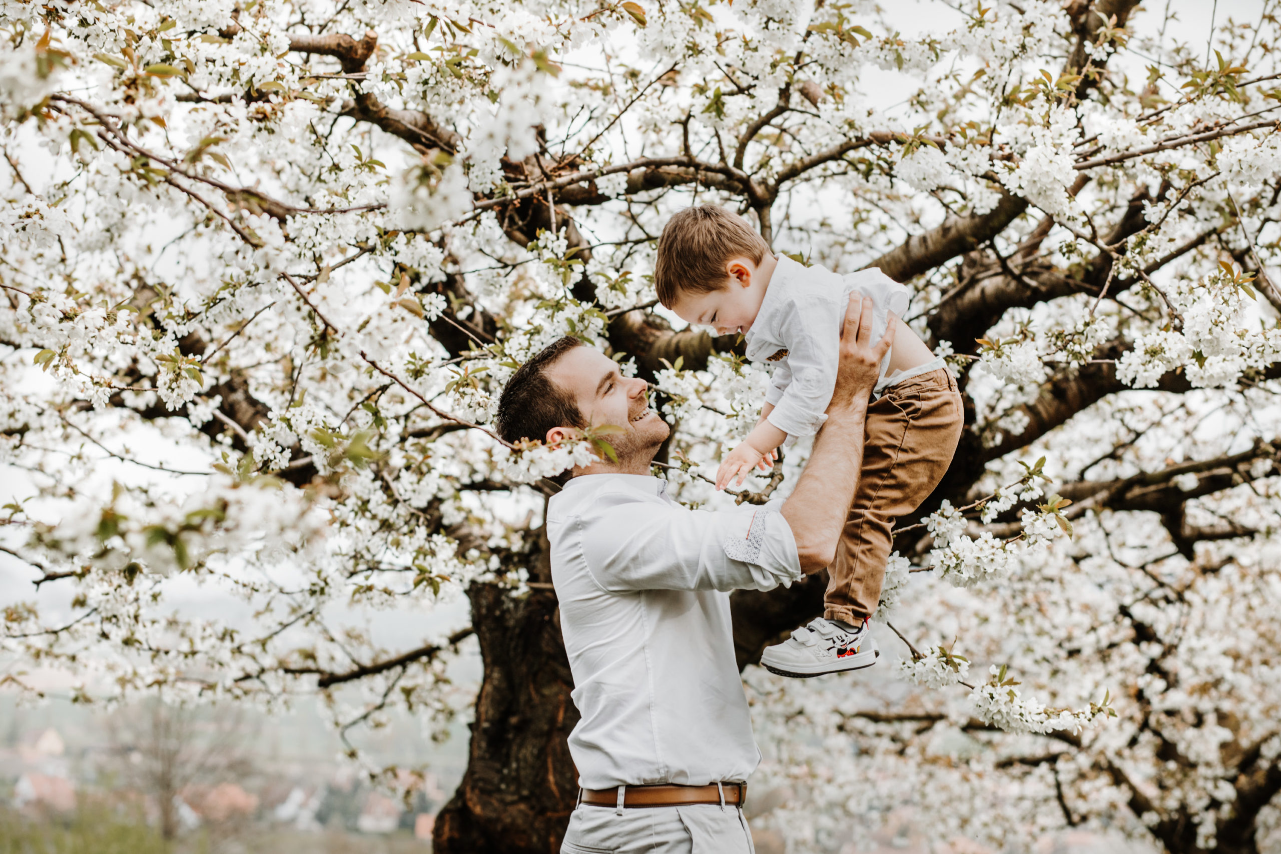 un papa joue avec son fils dans les arbres en fleurs