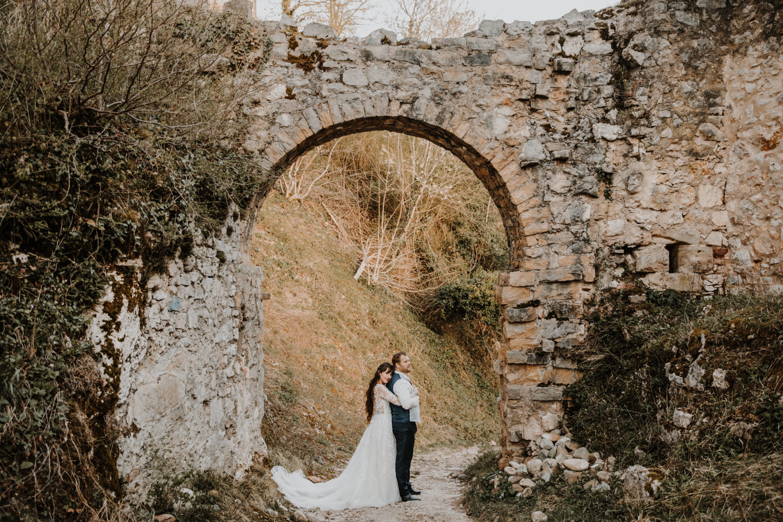 les mariés enlacés sous l'arche d'entrée d'un château en ruine