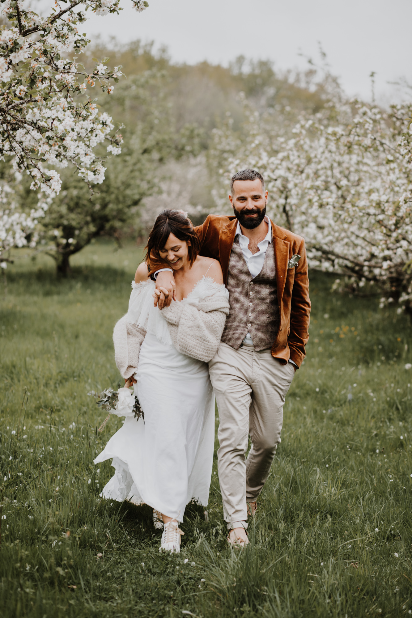 les mariés marchent dans un verger en fleurs domaine saint loup