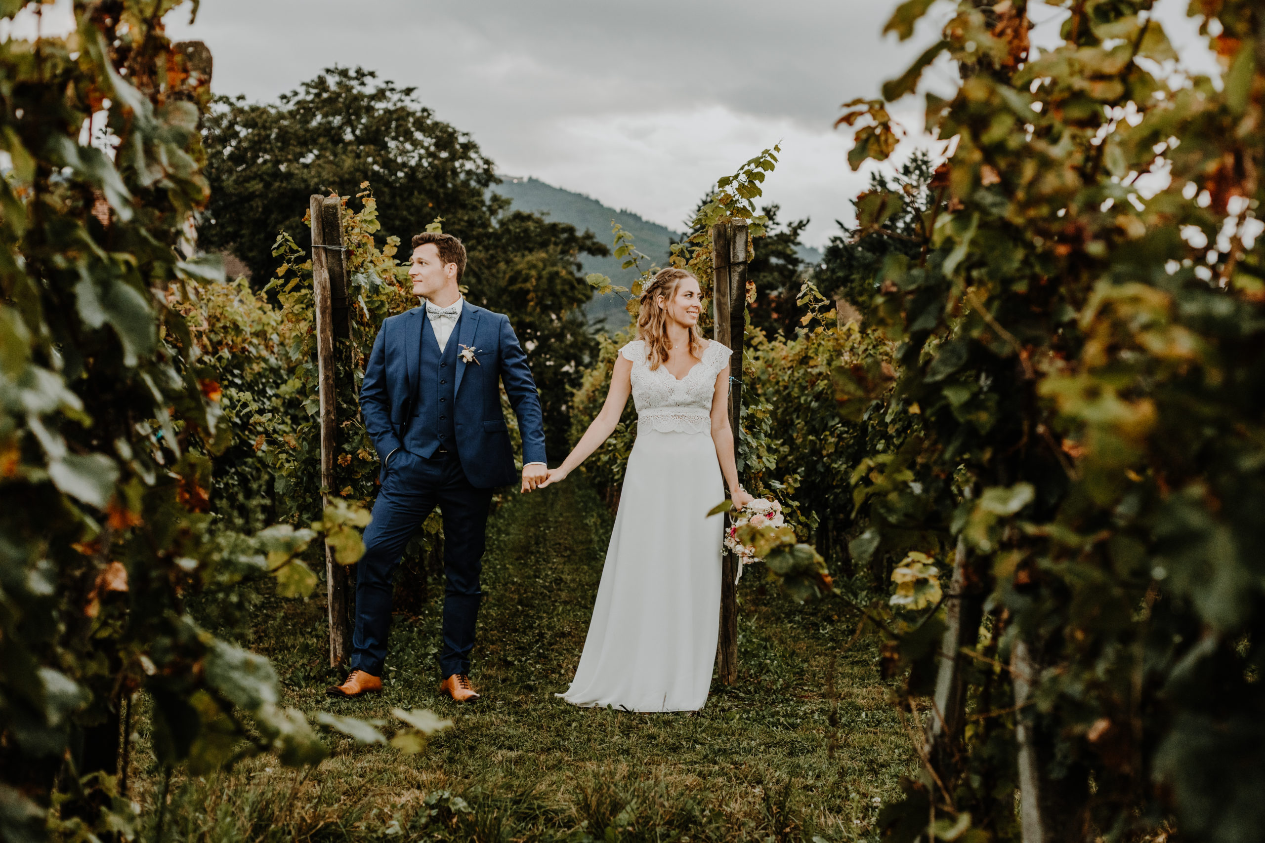 couple de mariés dans les vignes sous un ciel orageux