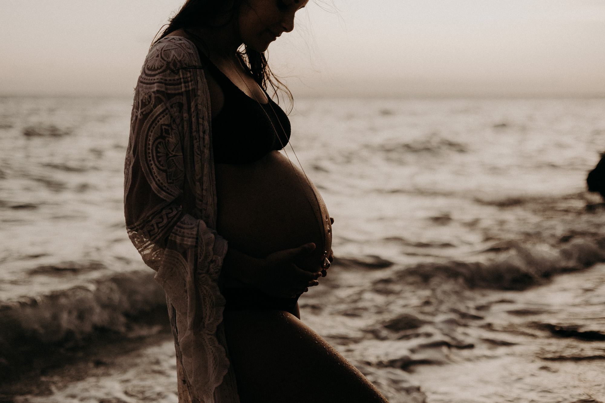 silhouette d'un ventre de femme enceinte au bord de la mer au coucher du soleil