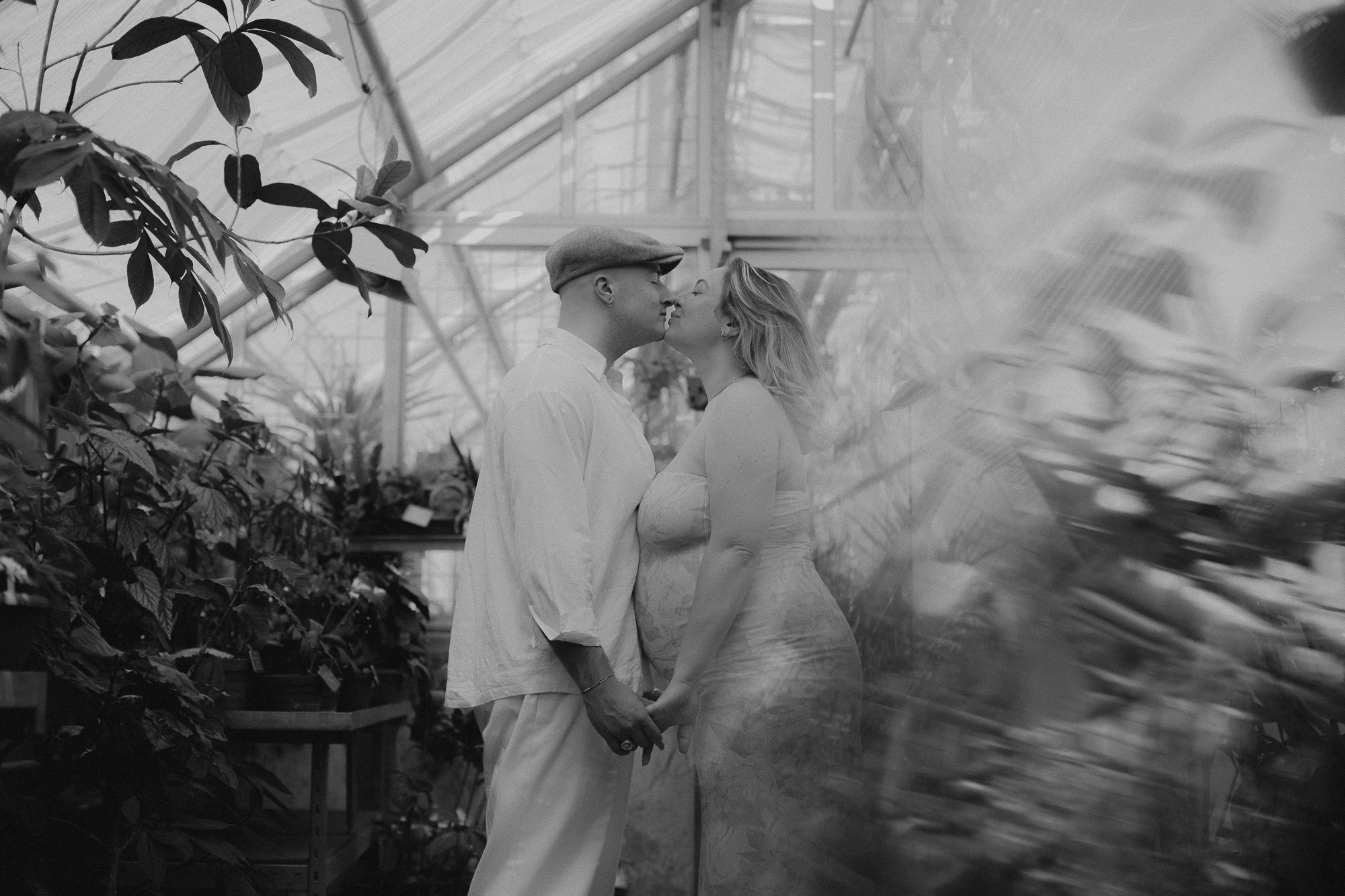 couple et femme enceinte s'embrassent dans une serre tropicale