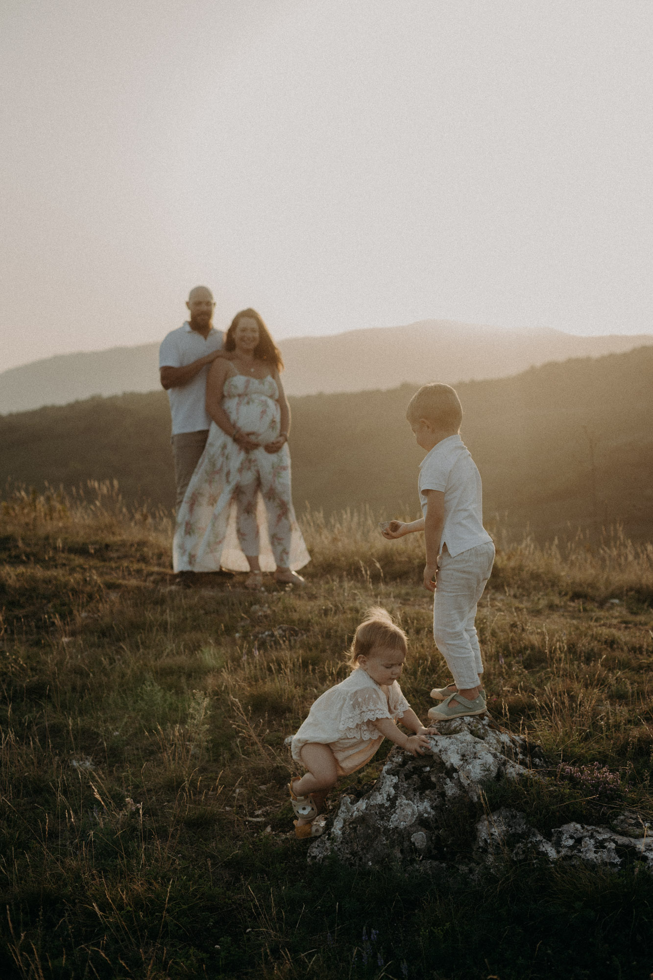 femme enceinte au ventre dénudée assise sur la plage au coucher du soleil