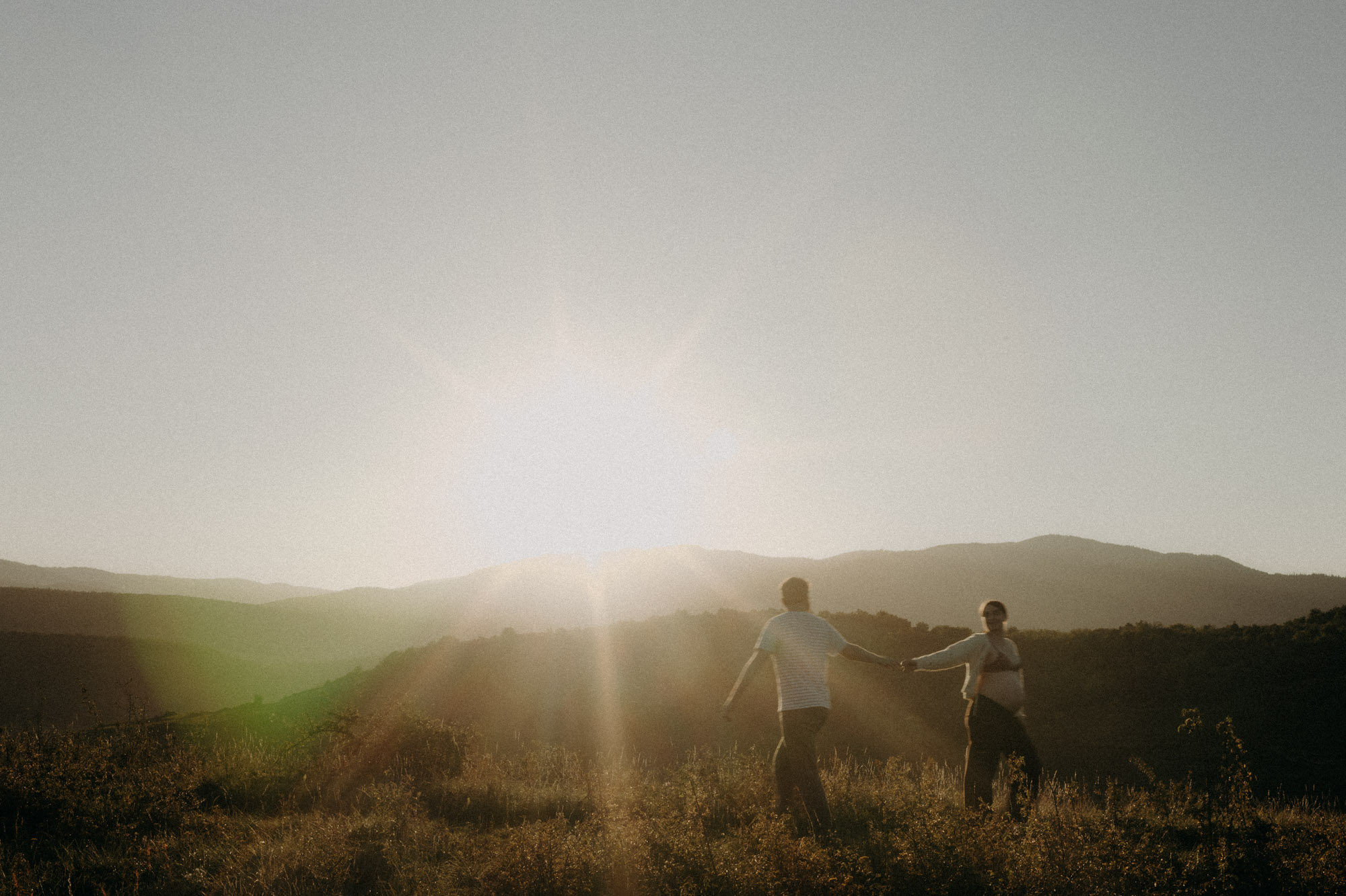 femme enceinte et son mari enlacées dans un paysage de vignes en alsace au coucher du soleil